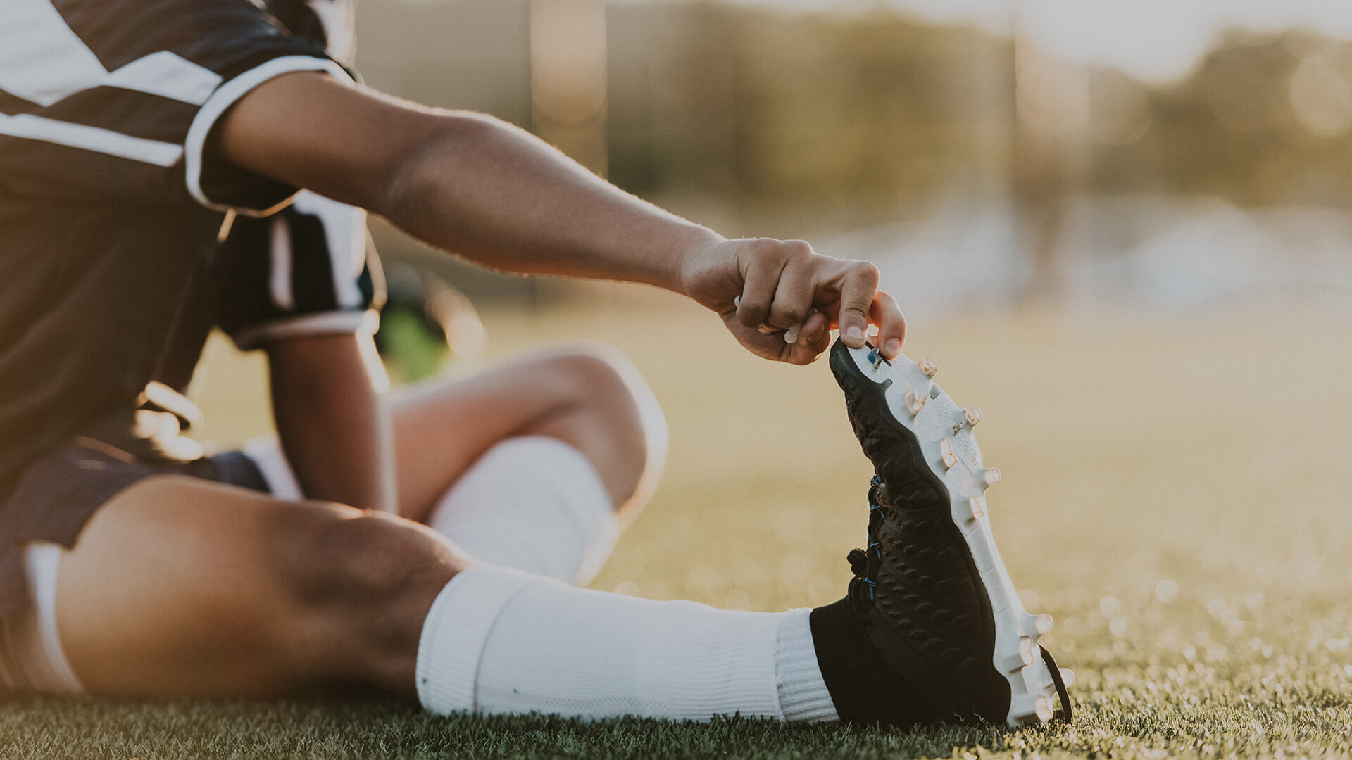 person in soccer uniform doing calf stretches