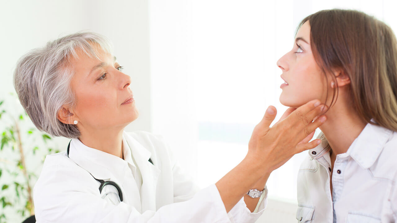 Endocrinologist feeling a young women's thyroid gland