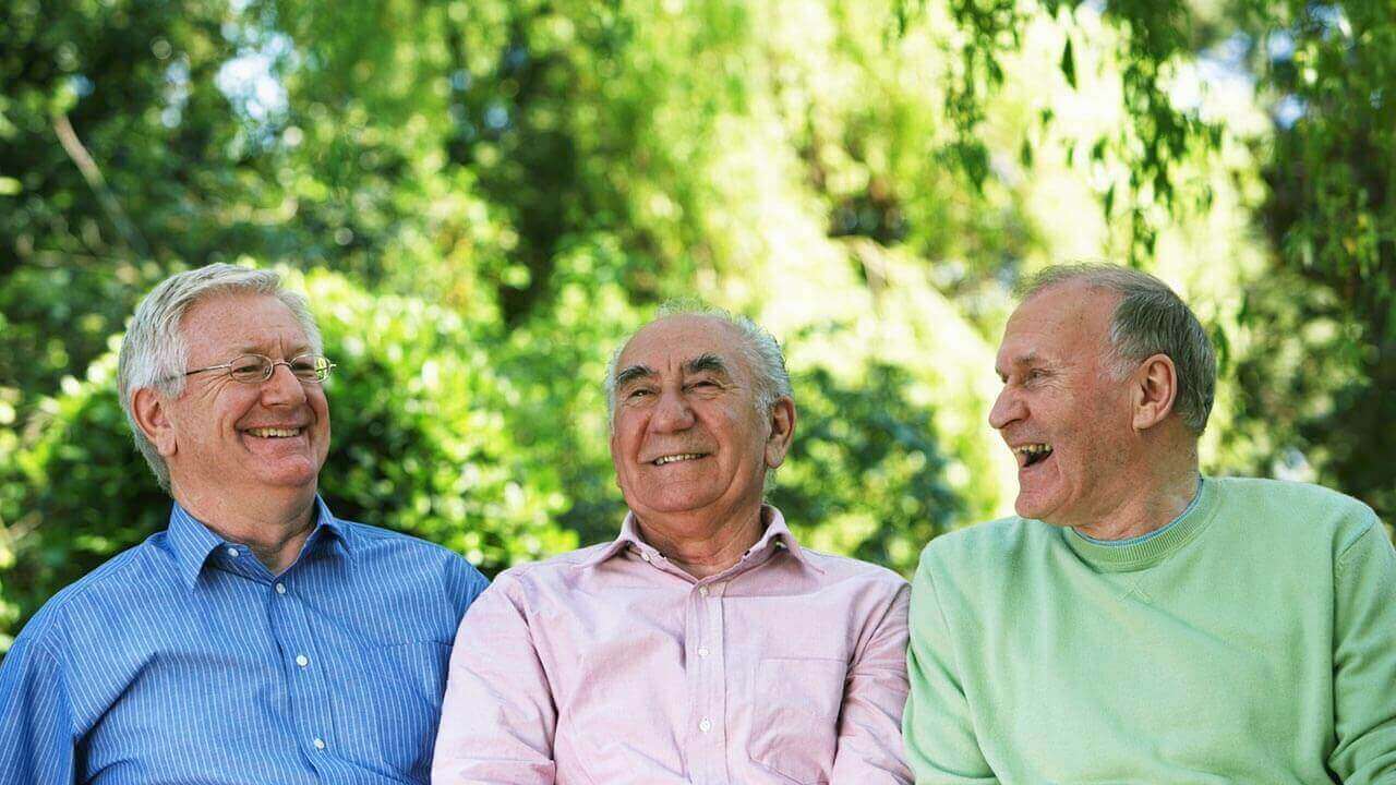 Three middle aged men sitting together outside
