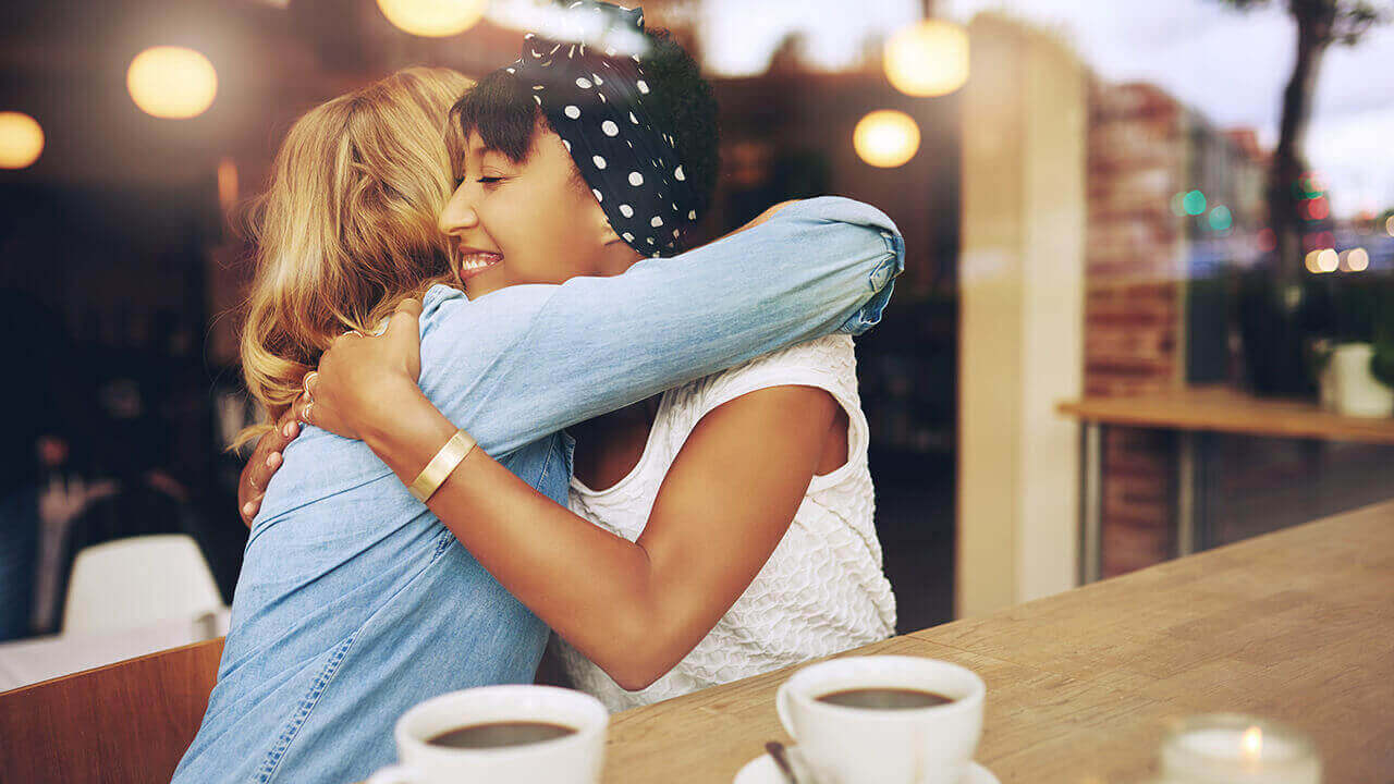 Two women hugging in a cafe