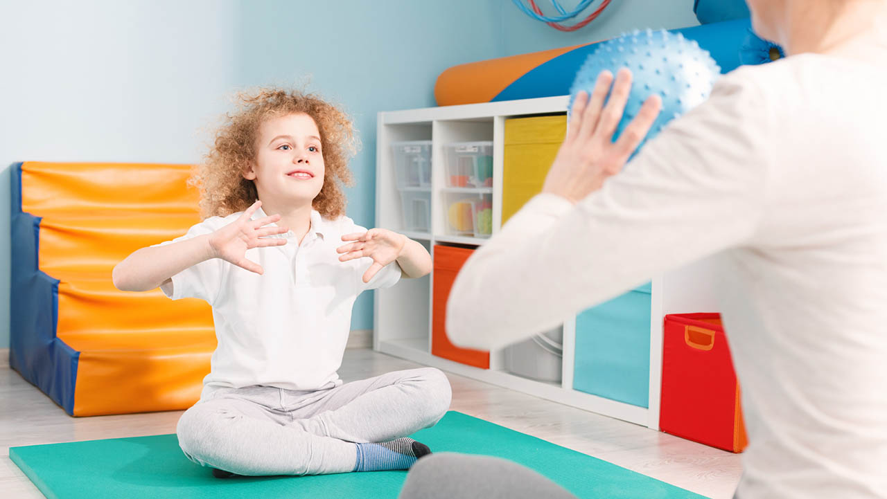 Child throwing a ball with a therapist