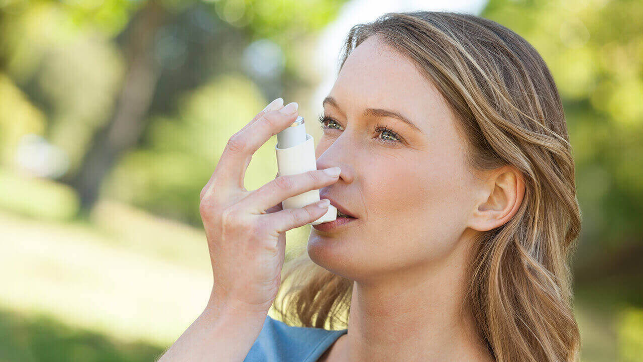 Young woman using an asthma inhaler