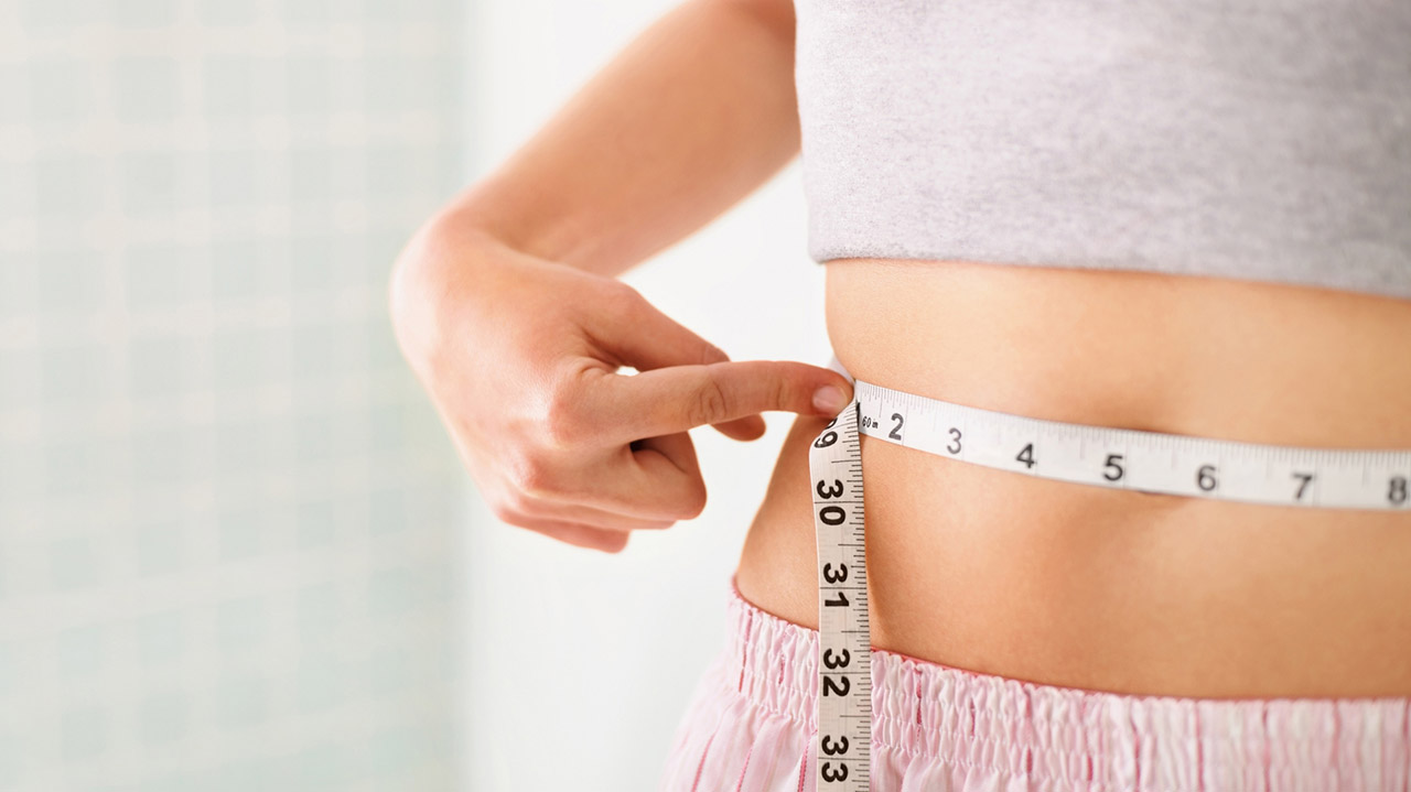 woman with measuring tape around stomach