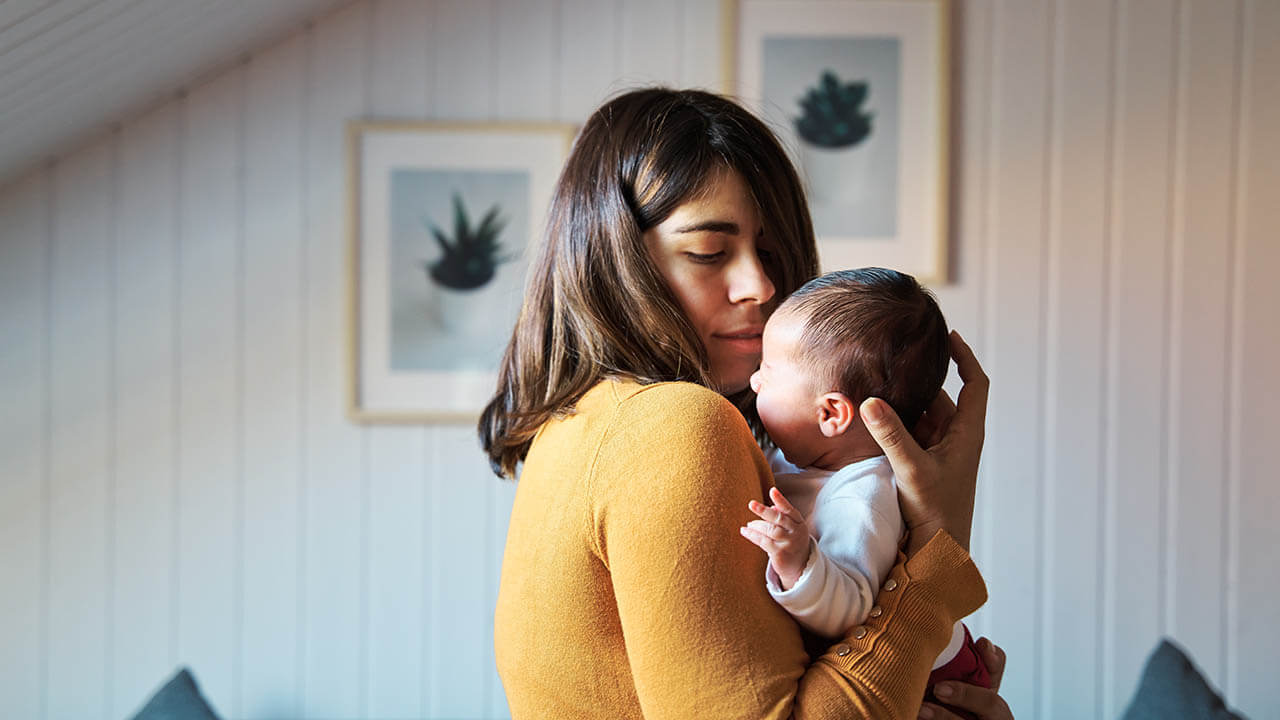 young woman holds her newborn boy in her arms