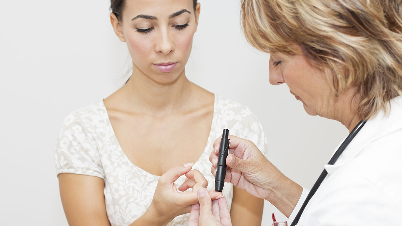 Female doctor testing for diabetes on a female patient