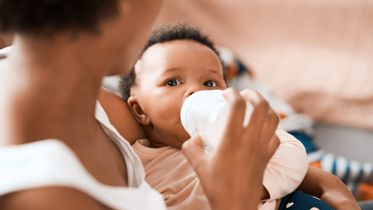 Young black mother feeding her infant with a bottle