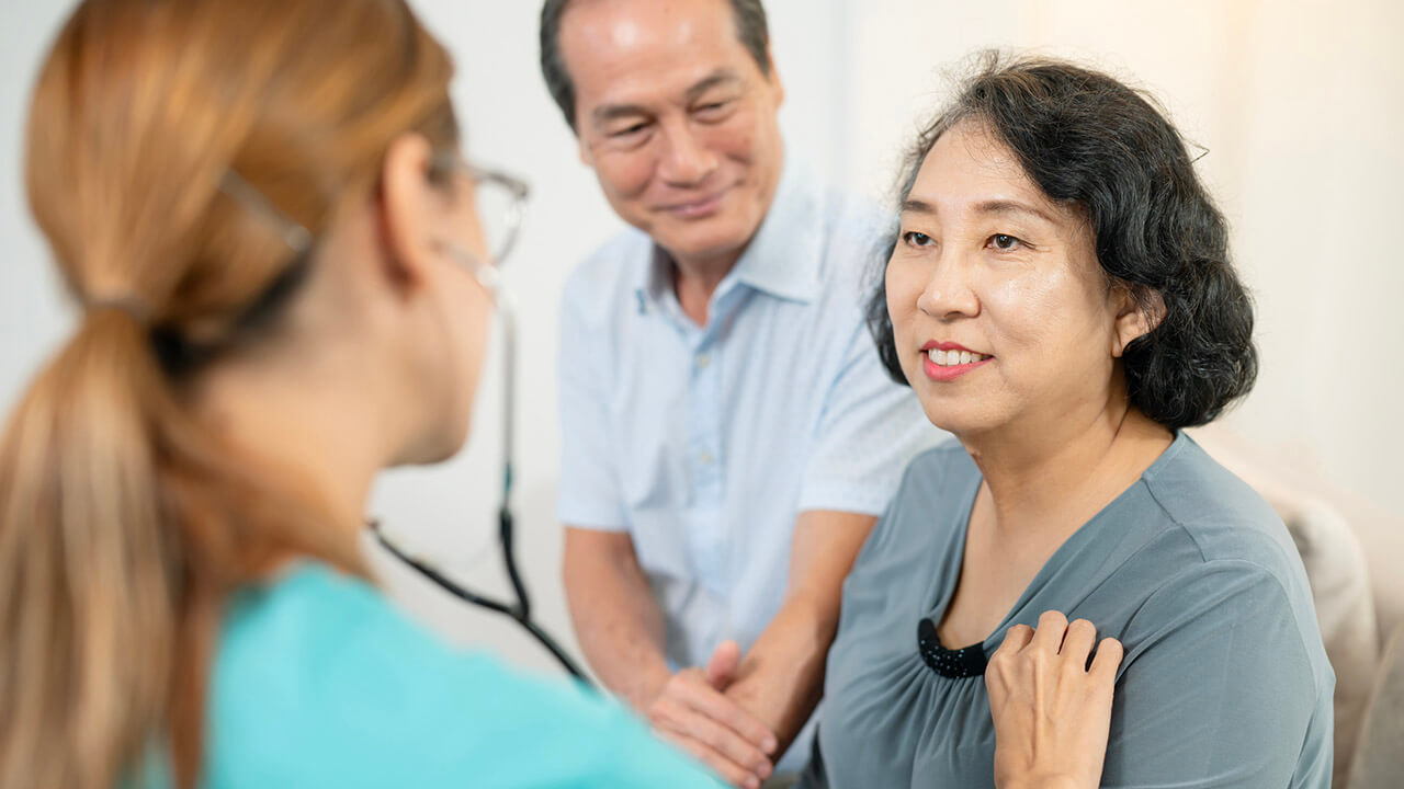 Female nurse listening to senior female patient's heart with stethoscope