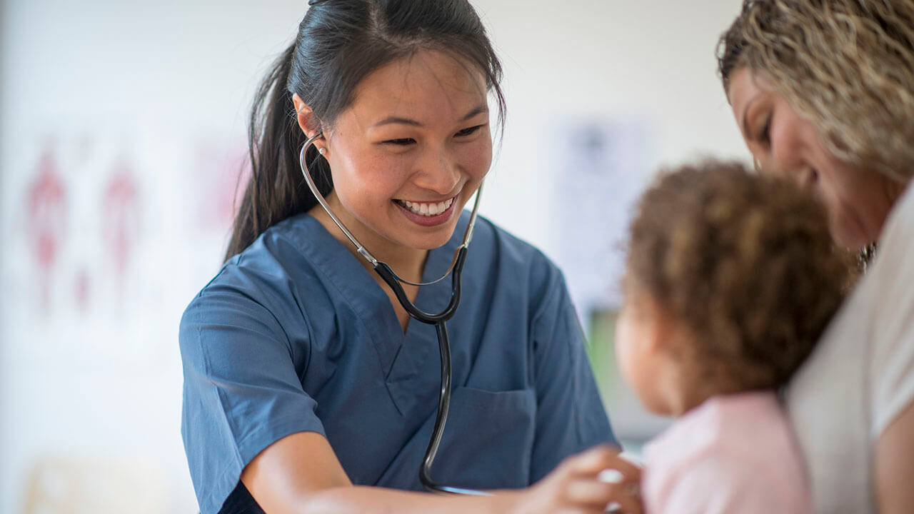 Female nurse listening to a child's heart with stethoscope