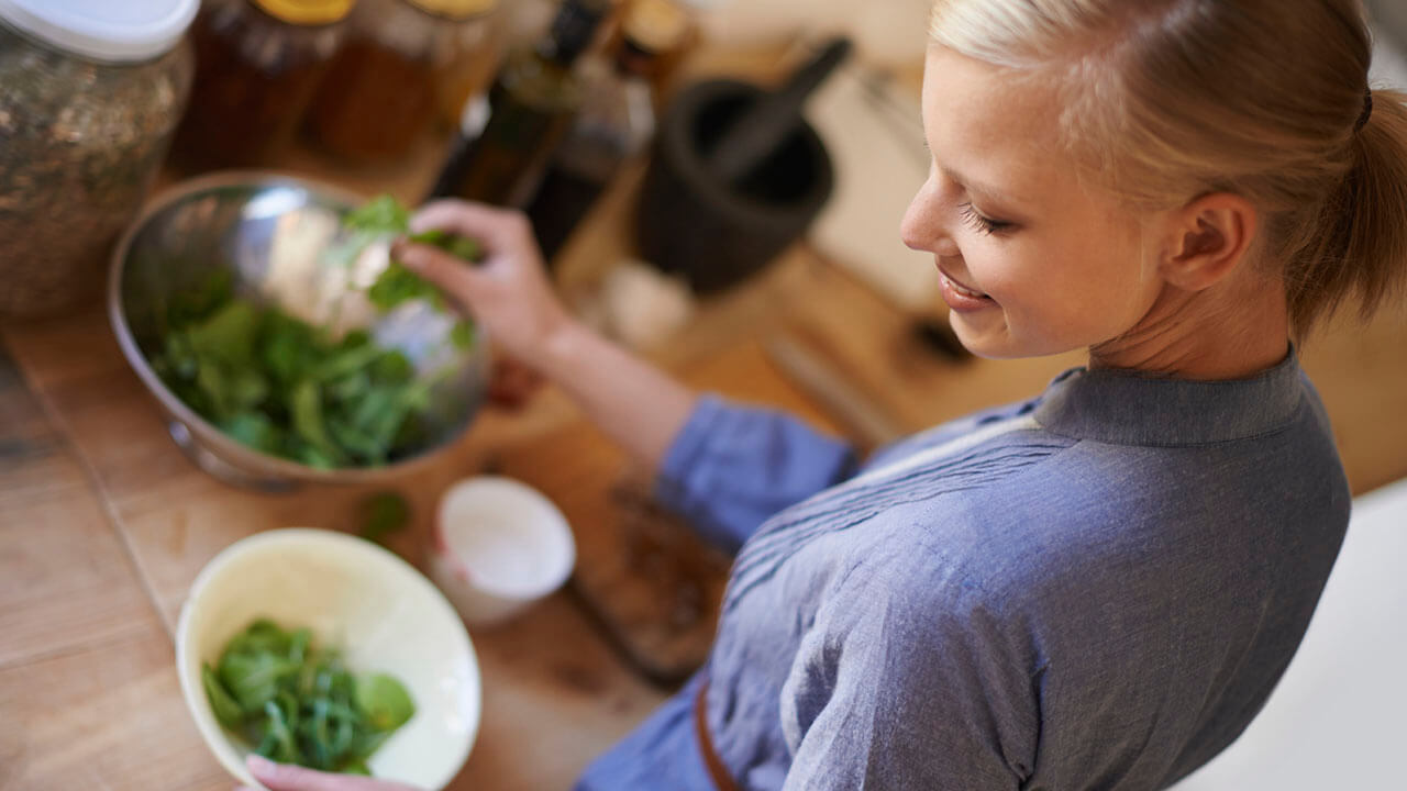 Woman holding a bowl of fresh green vegetables