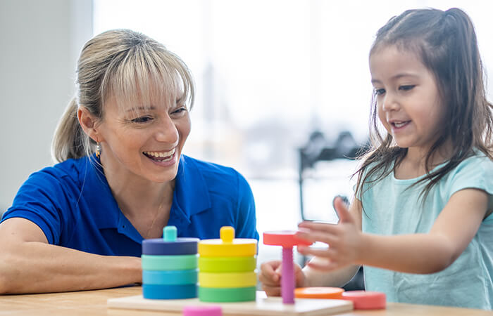 female therapist playing with a stacking game with a young Hispanic child 