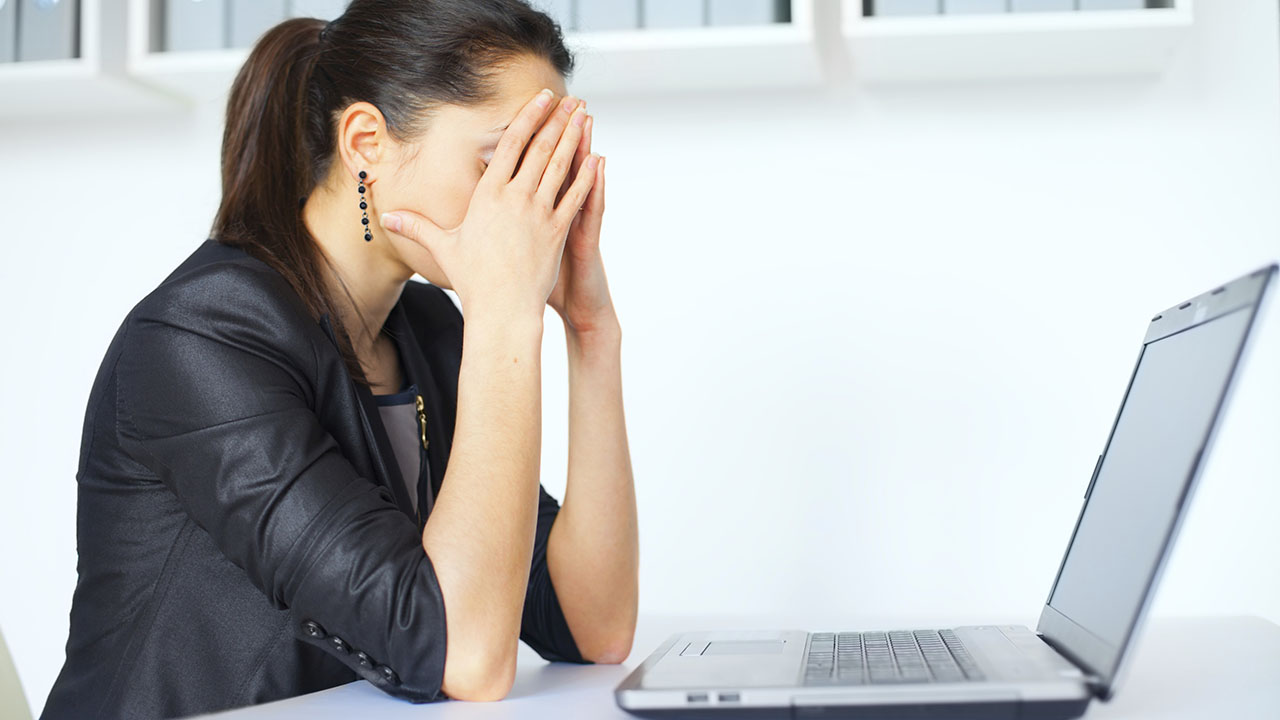 Businesswoman stressed sitting at her desk with laptop