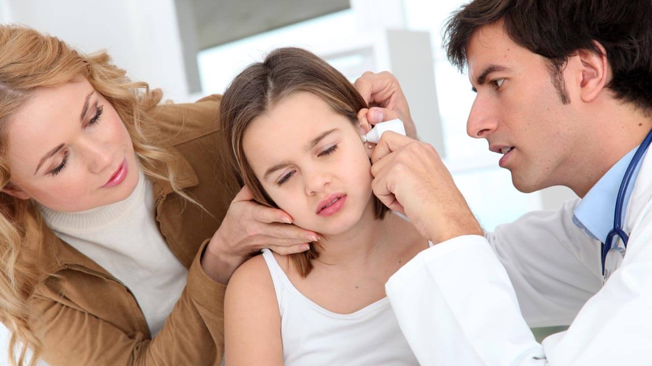 Mother looking at daughter concerned while a doctor looks at the child's ear