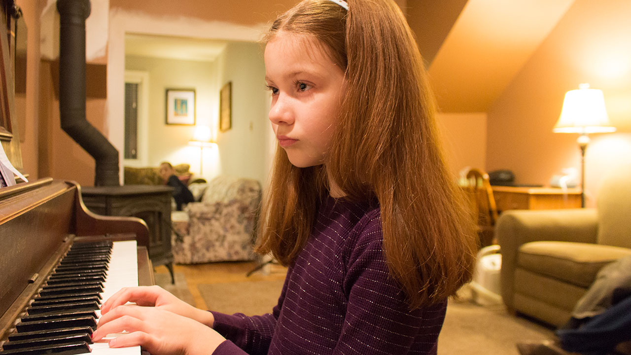 Marian playing the piano in a living room