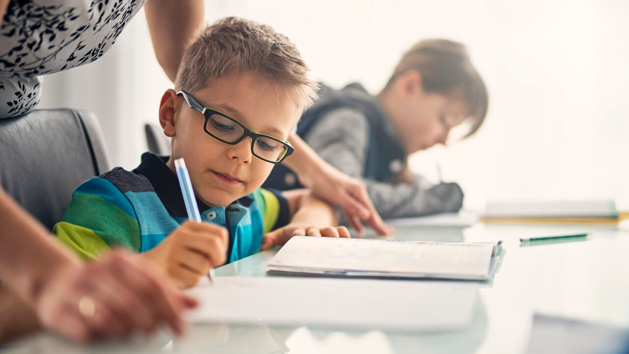 A child wearing glasses working on schoolwork.