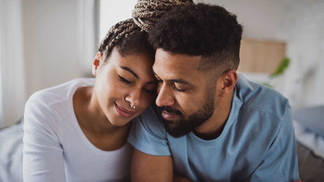 Young black couple leaning on each other smiling