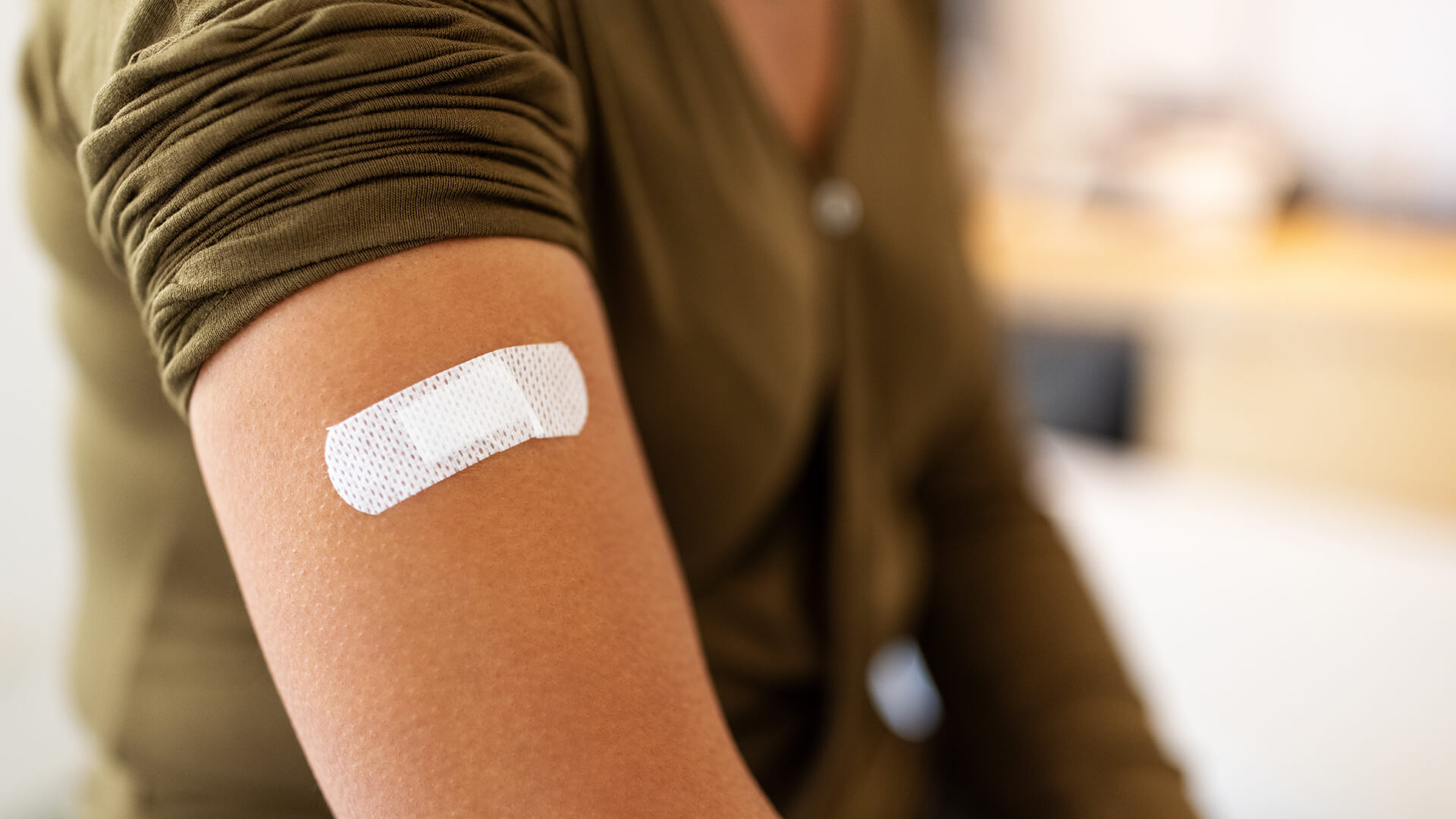 person wearing green shirt with bandaid on