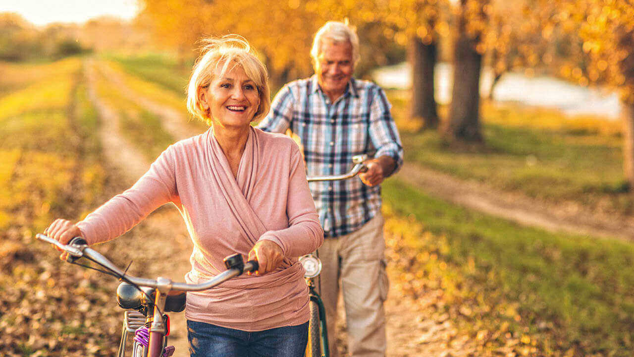Middle age couple walking their bikes outside in autumn