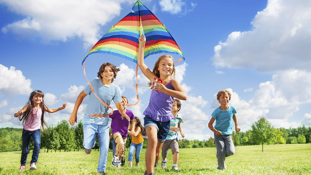 Group of children running and flying a kite