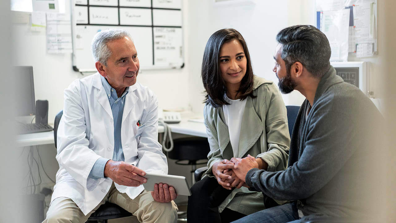 Young couple talking to male doctor with a clipboard