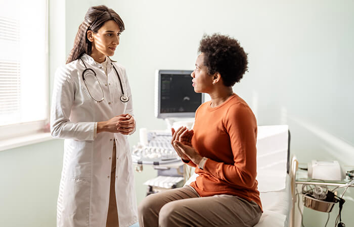 young female doctor speaking to young female black patient in exam room