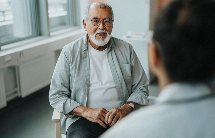 Middle age man sitting in a chair in a medical office talking to a doctor
