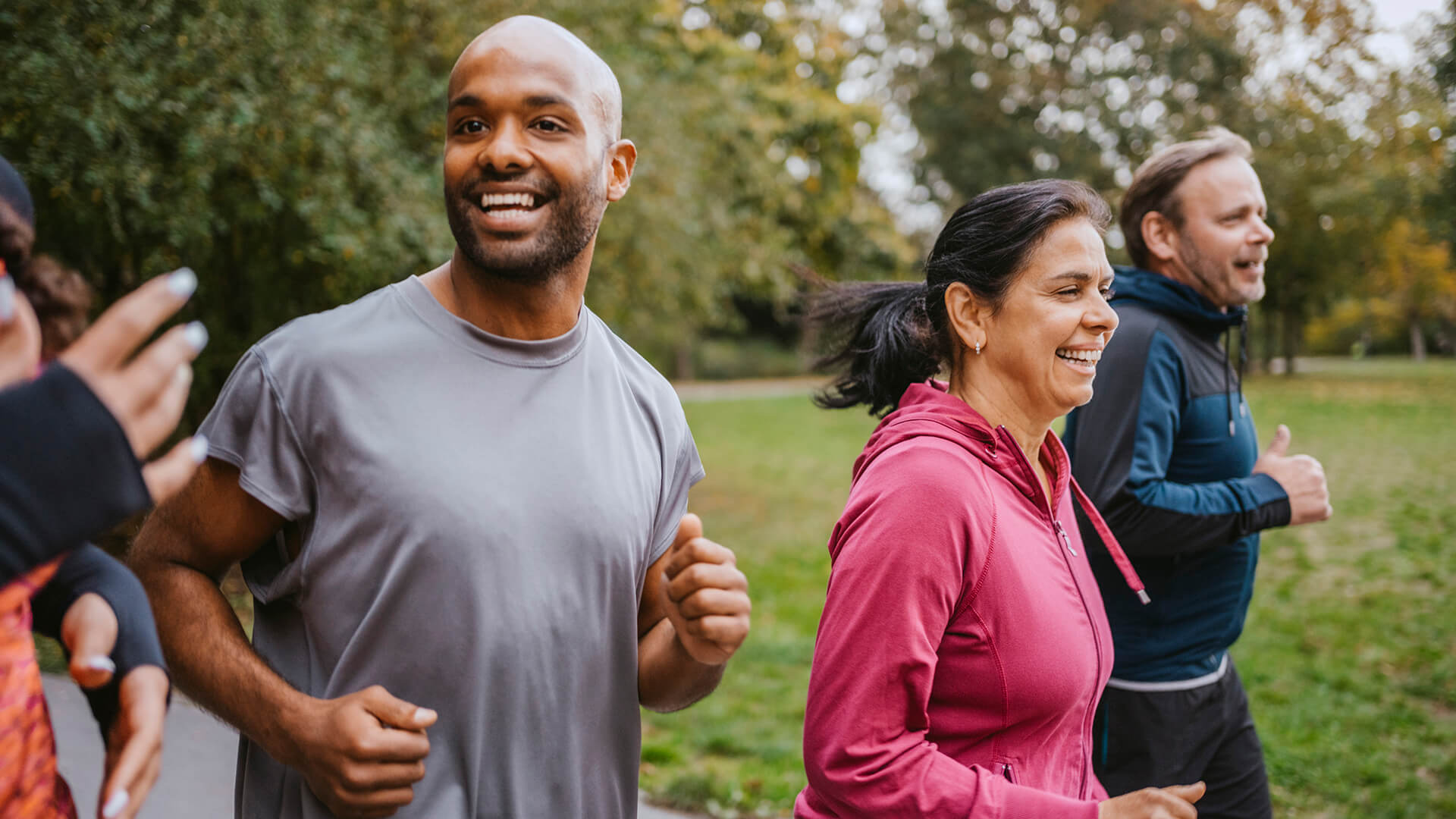 Cheerful male and female friends running at park