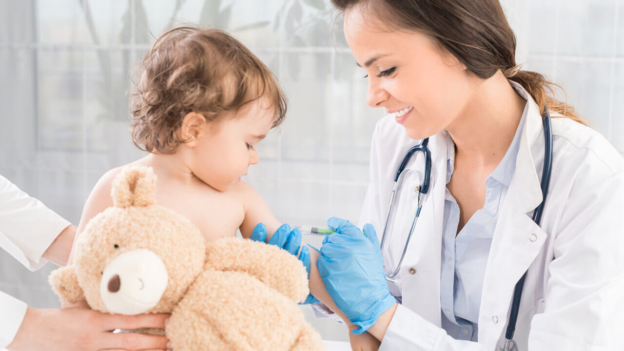 Young female doctor giving baby a shot