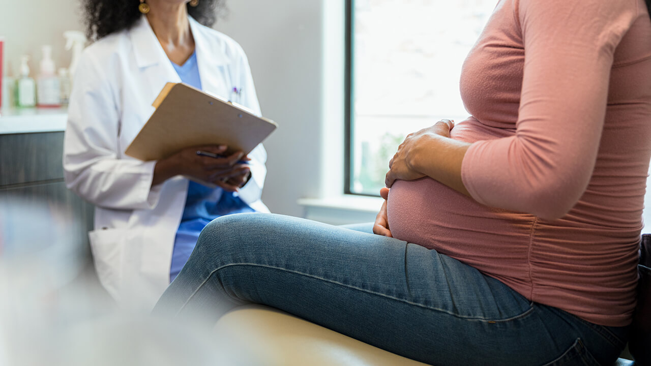 Unrecognizable pregnant woman and female doctor have discussion during appointment