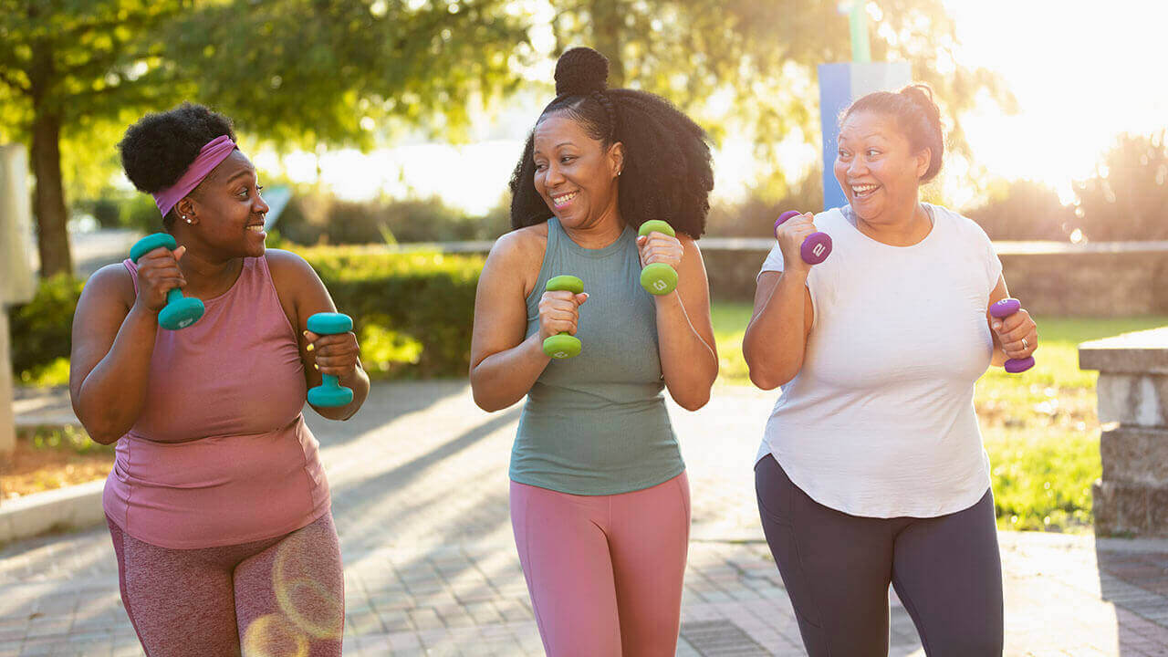 group of women walking outdoors carrying weights