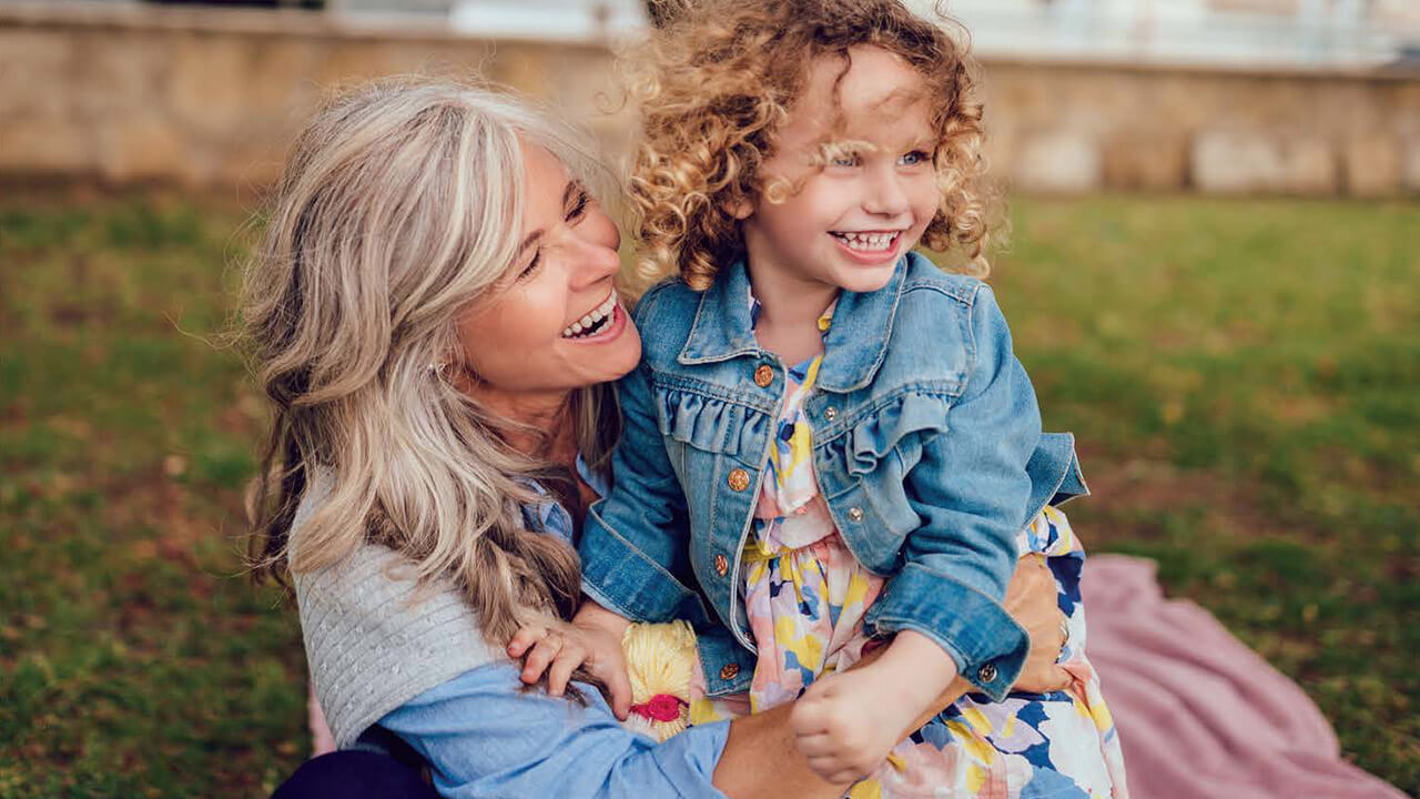 Middle age woman hugging granddaughter outside