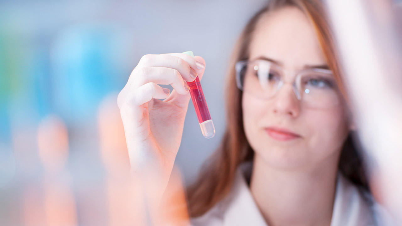 Female laboratory technician looking at a vial of blood