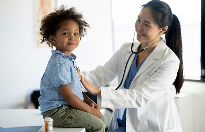 female physician with young boy checking heart with stethoscope