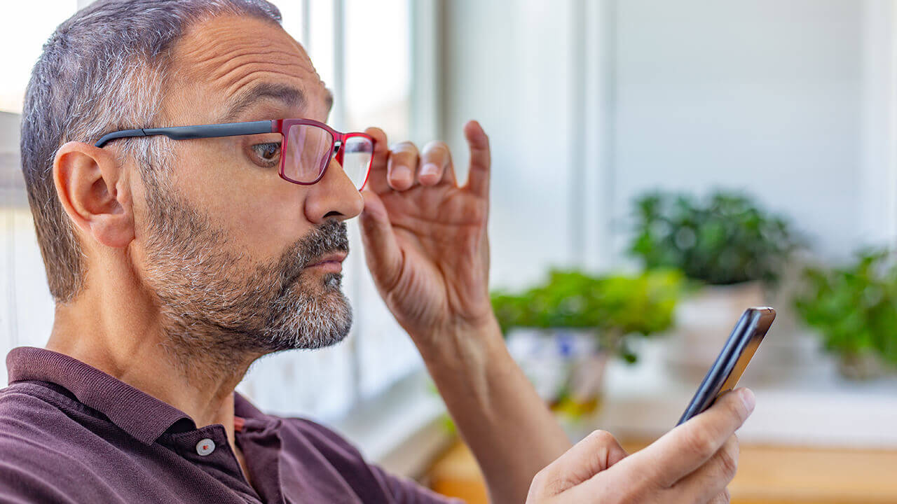 middle-aged man reading phone with bifocal glasses