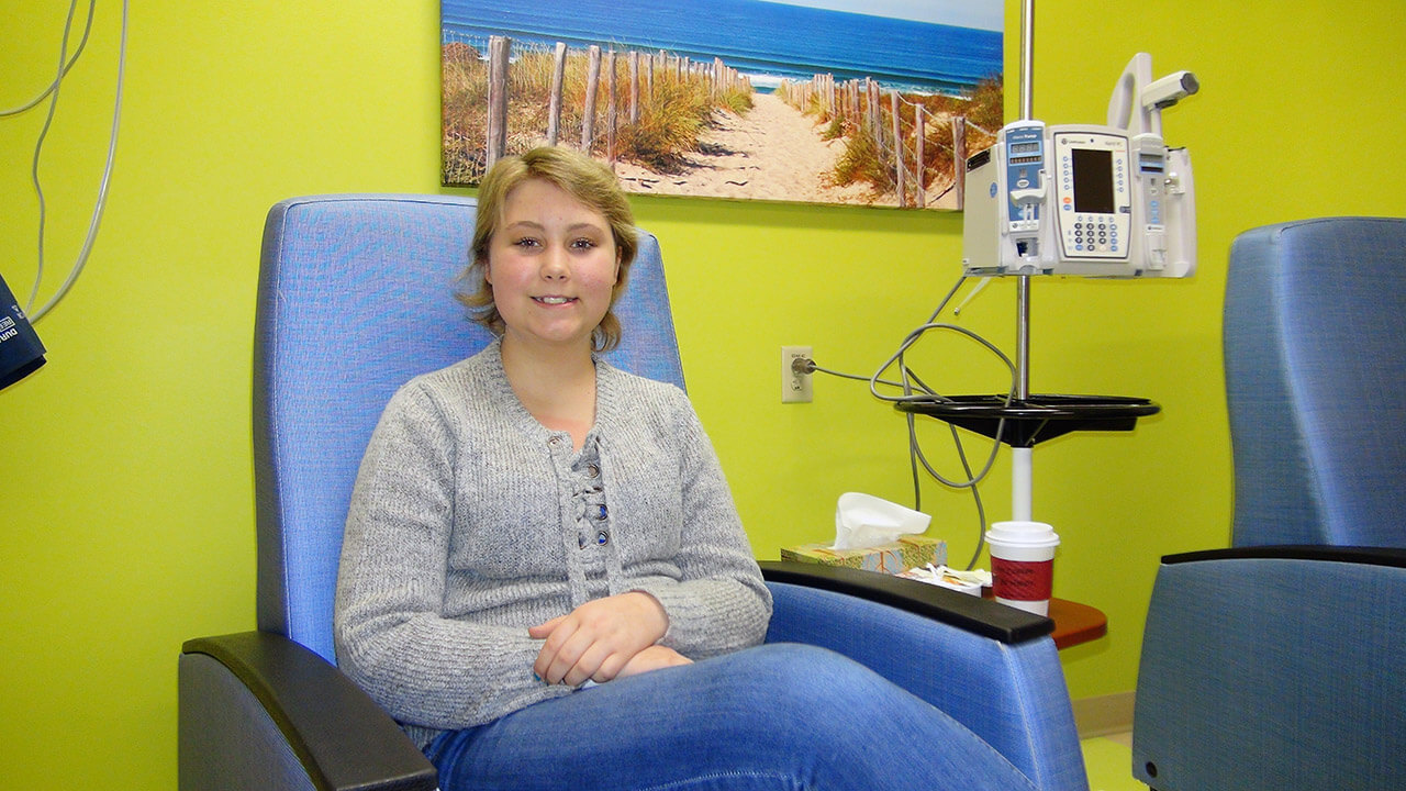 Patient Natalie sitting in a chair smiling at the camera