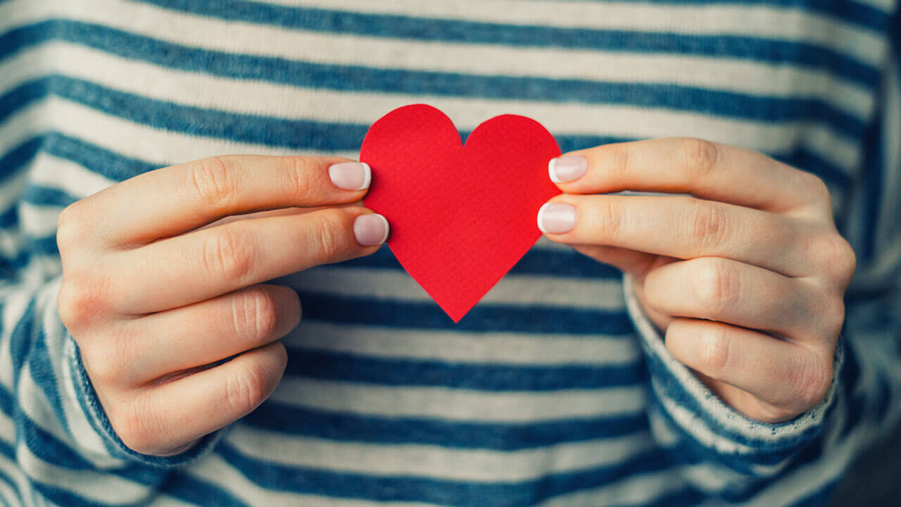 Woman holding a red paper heart in her hands