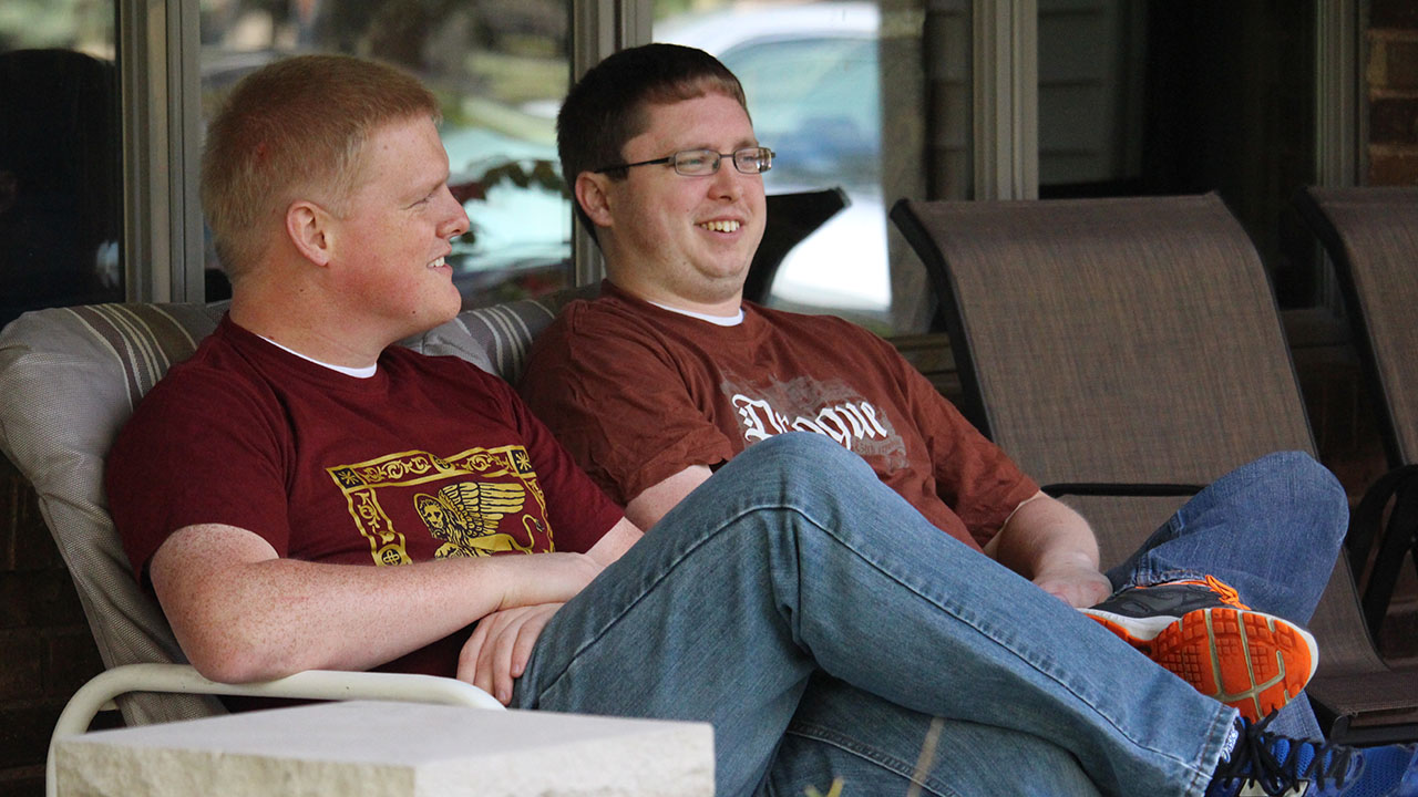 Michael sitting in a chair on a porch with a friend