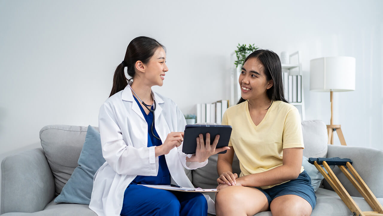 female nurse with ipad talking to female patient in yellow shirt