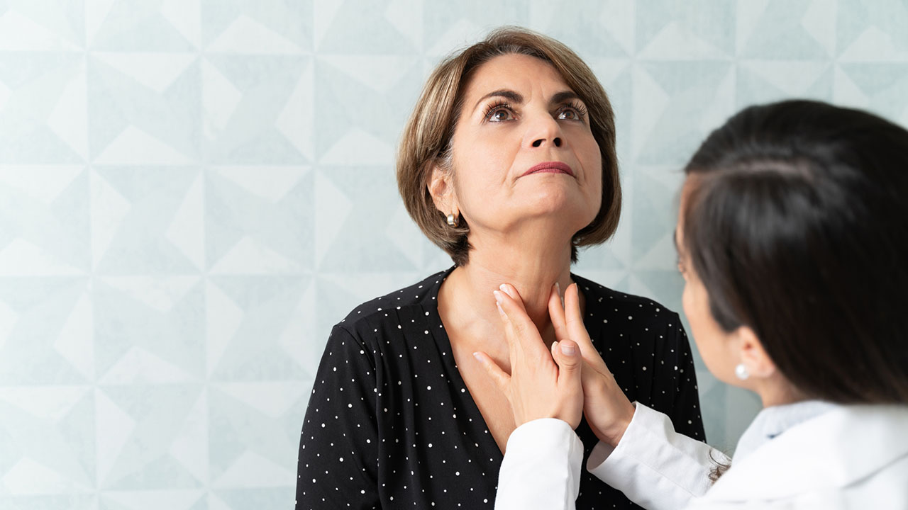 Female doctor feeling a female patient's thyroid gland