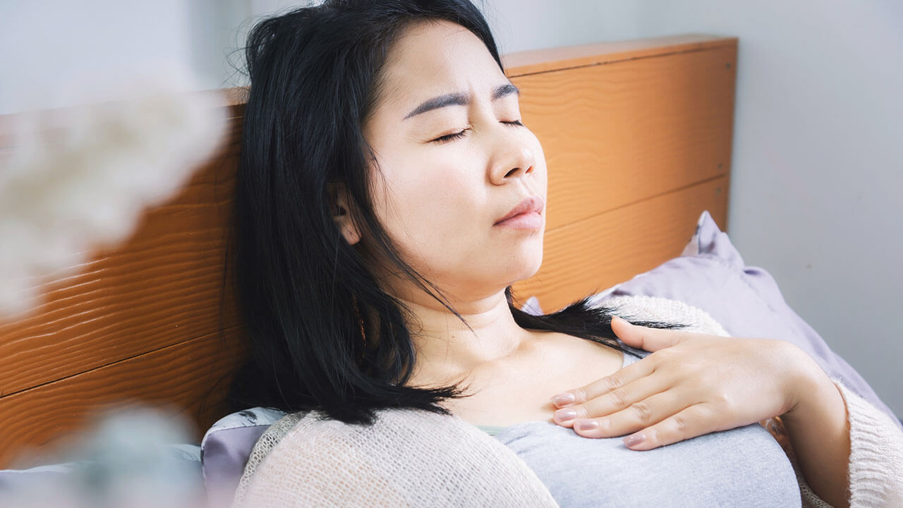 Woman laying in bed with hand on chest