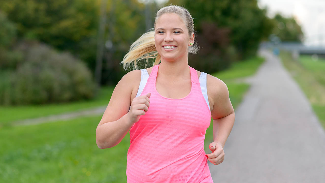 woman smiling running down a trail