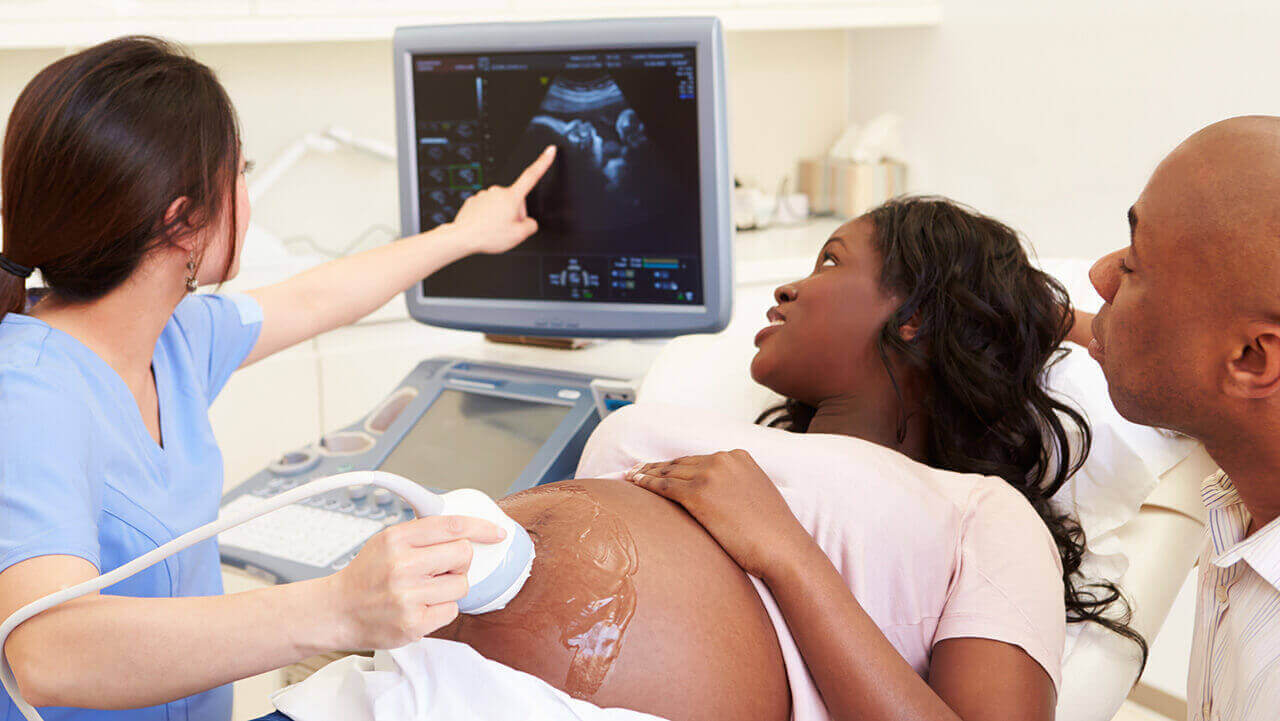 An ultrasound technician pointing at a fetal monitor