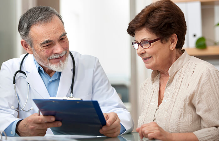 older male doctor helping older female patient go over chart 