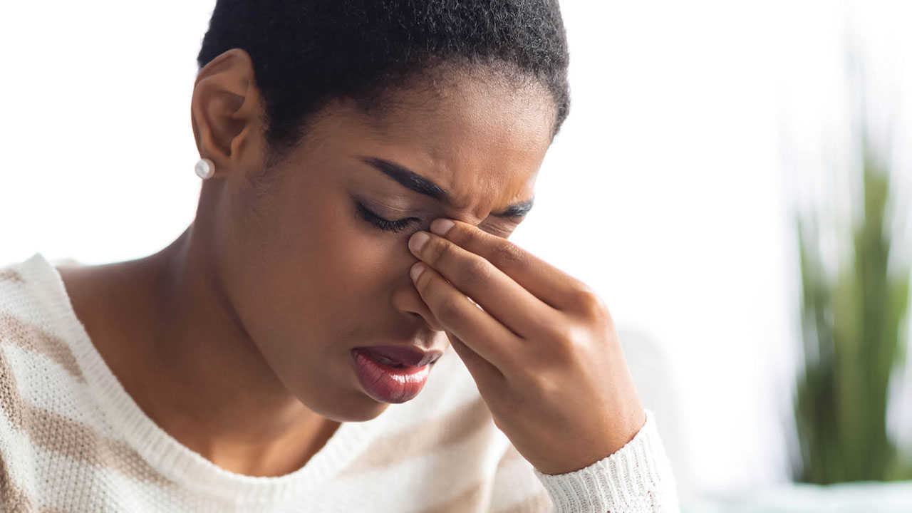 Young woman holding her nose in pain