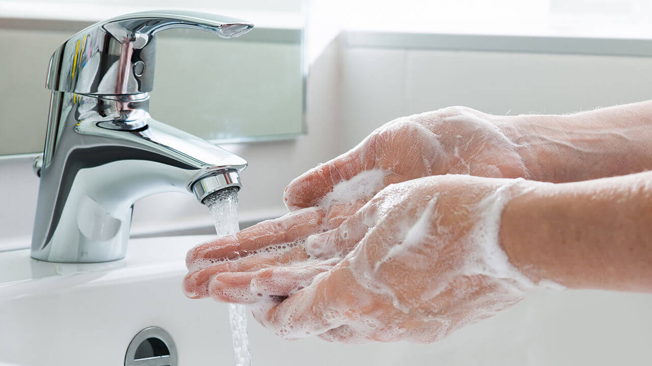 woman lathering her hands with soap in a sink of running water